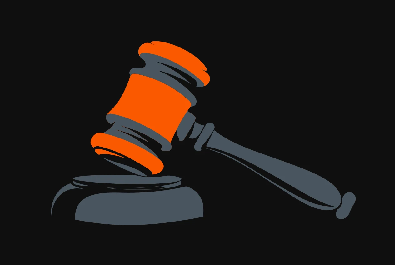 An auction gavel resting on its striking block, the head of the gavel coloured orange.
